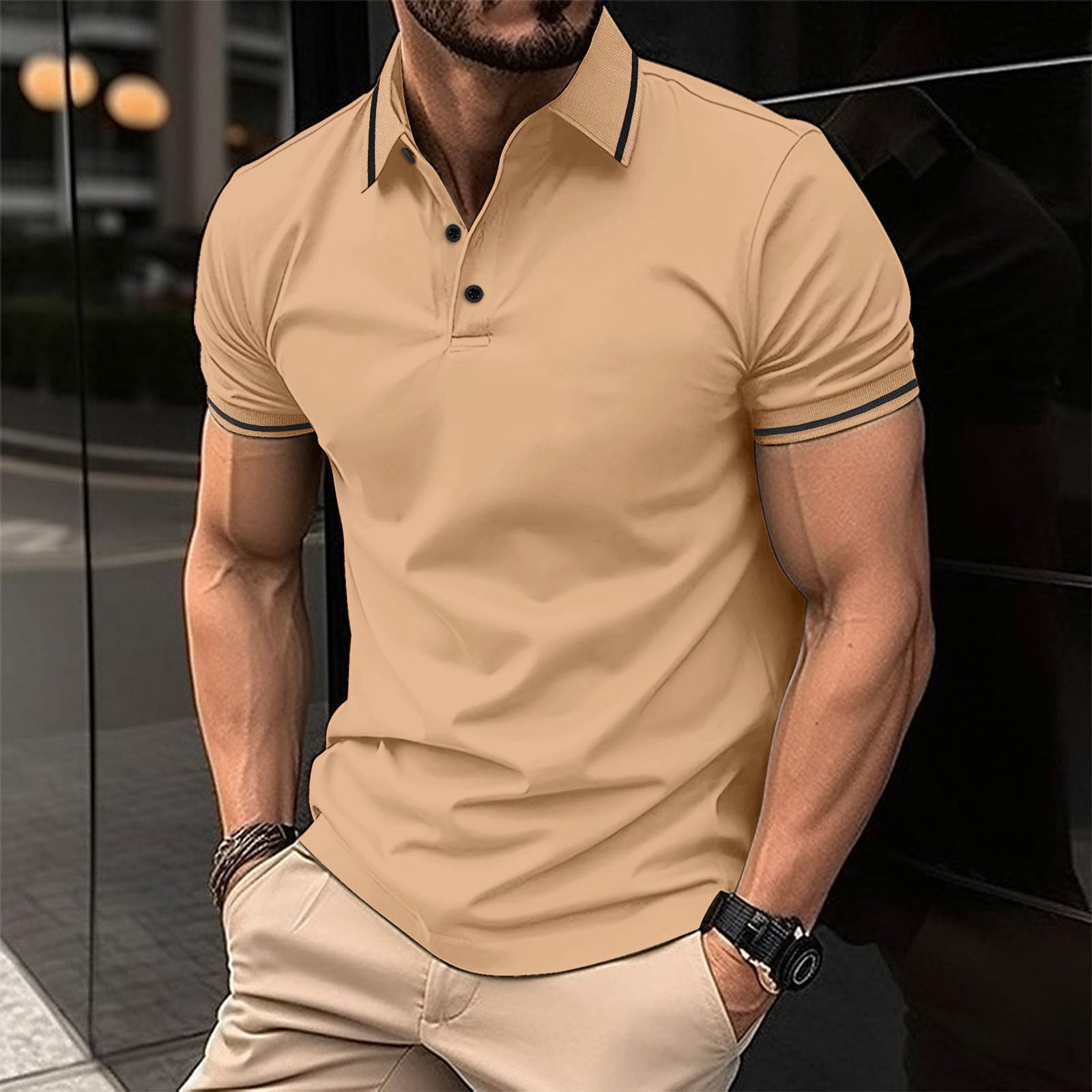 A man wearing a khaki polo shirt with contrast trim around the collar and sleeves, standing in a reflective indoor setting.