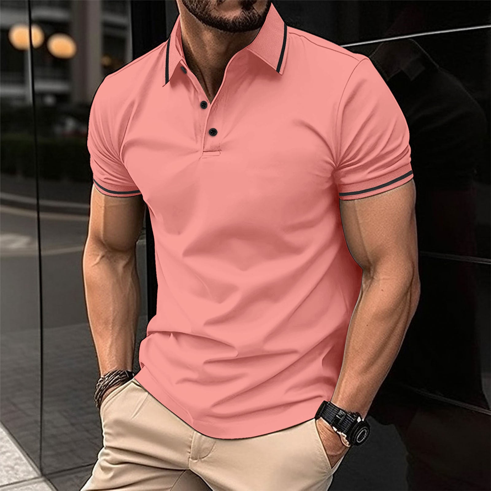 A man wearing a red polo shirt with contrast trim around the collar and sleeves, standing in a reflective indoor setting.