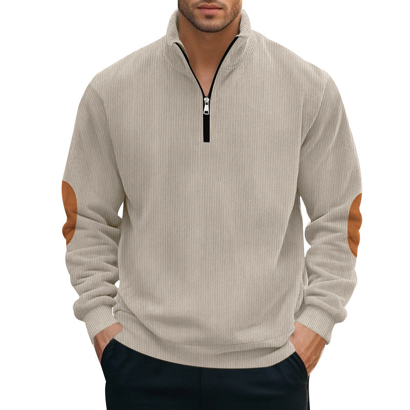 A man wearing a beige ribbed quarter-zip pullover with contrast elbow patches, paired with black pants.